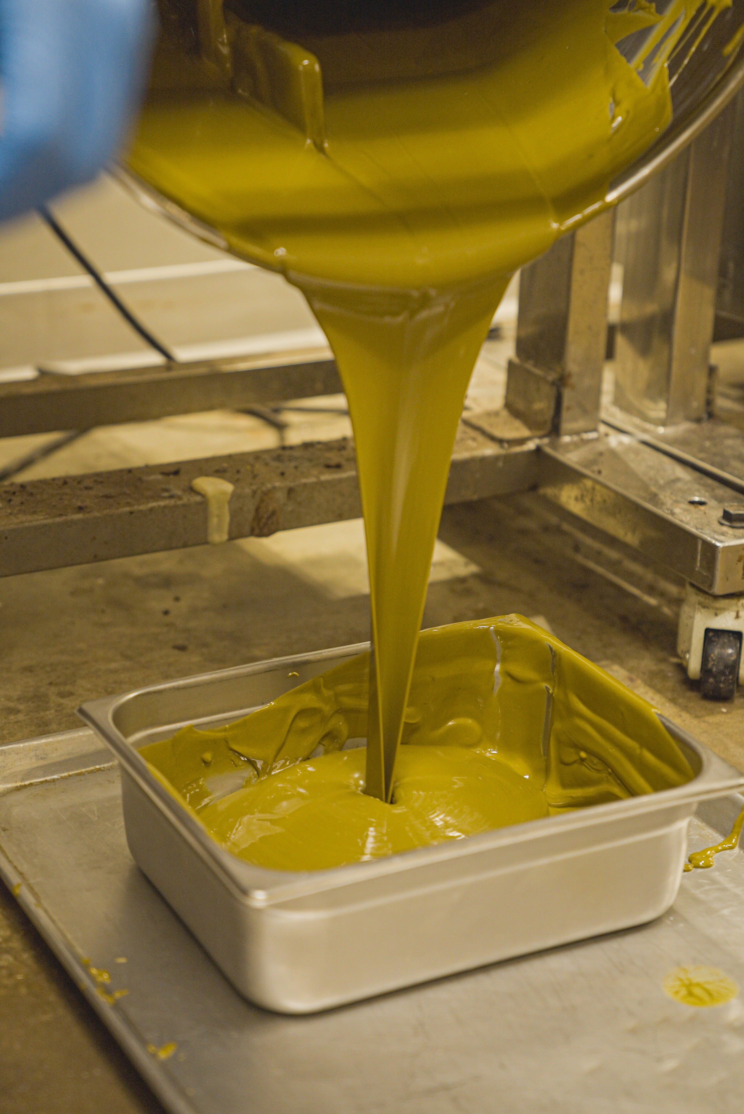 Dubai Pistachio paste being poured into a pan for mixing into dubai bars